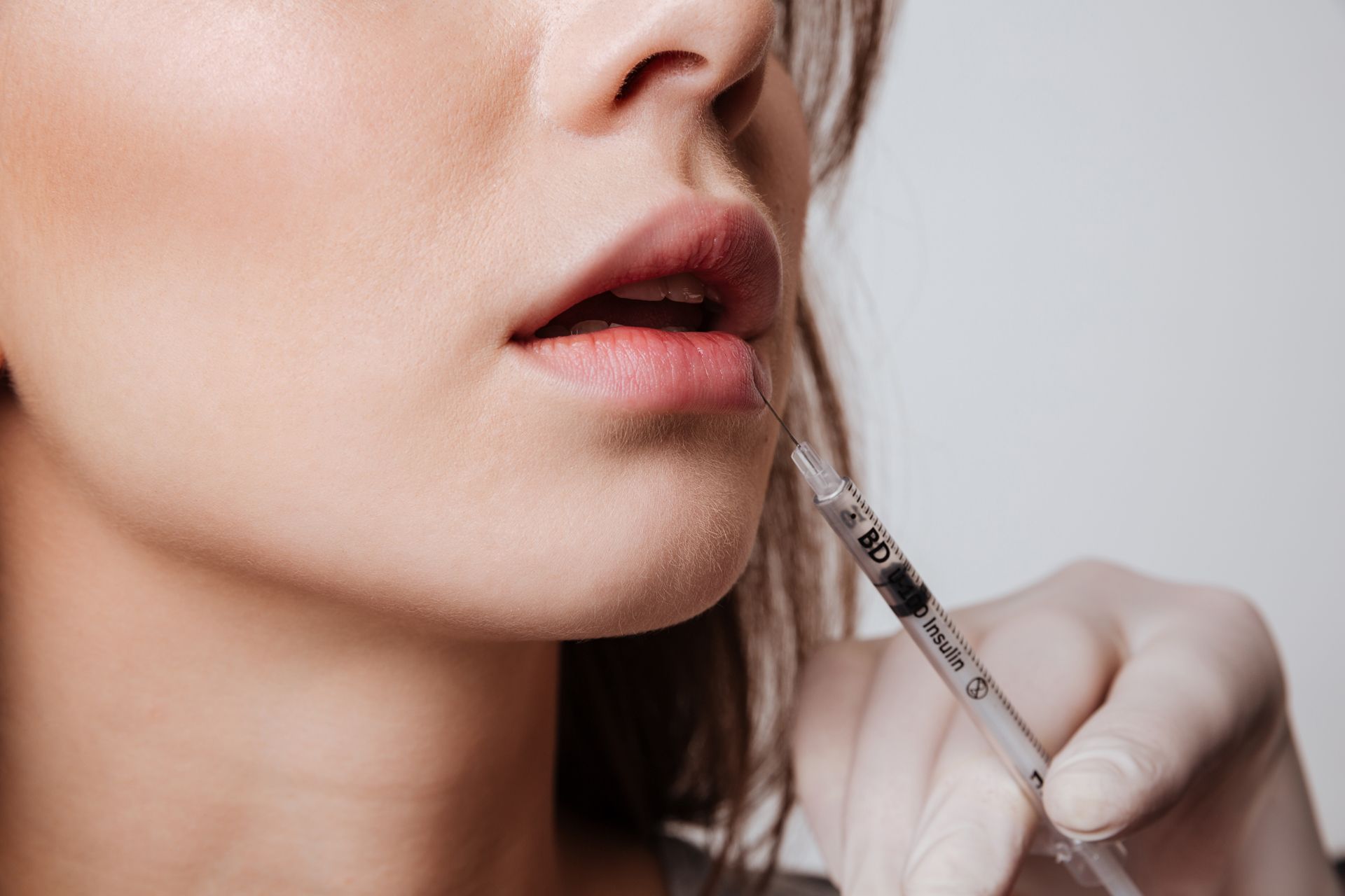 Close-up of a person receiving an injection in the cheek with a syringe