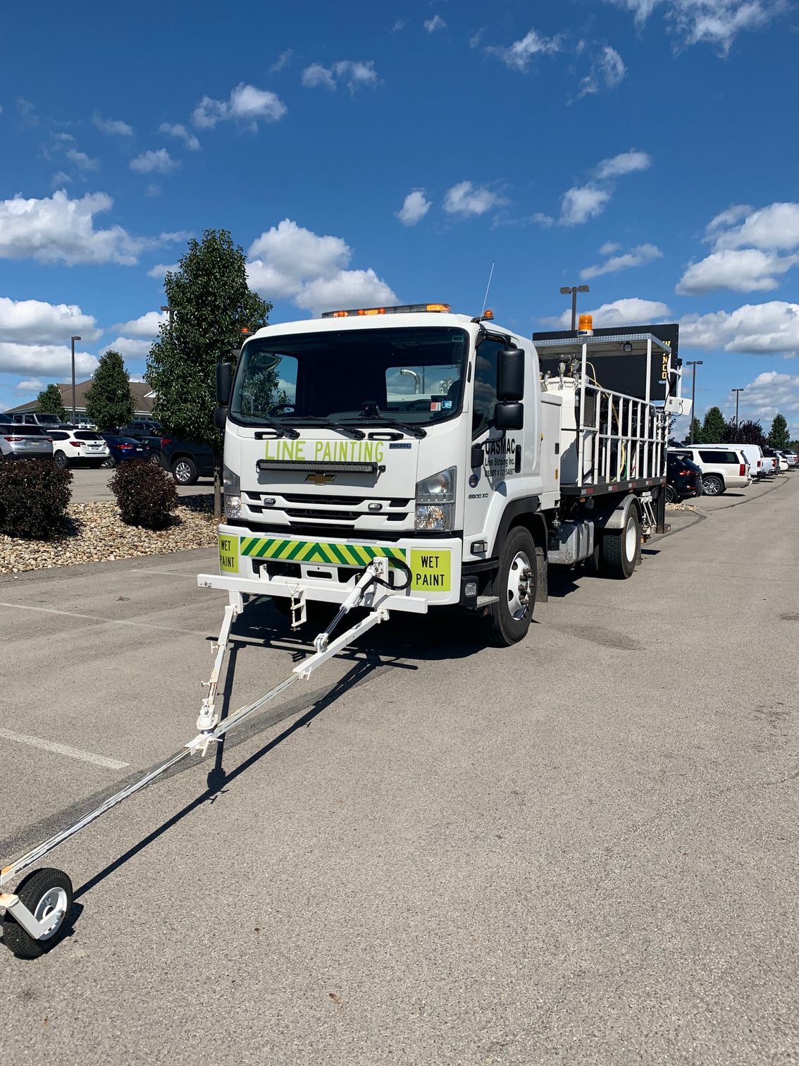 A white truck with a trailer attached to it is parked in a parking lot.