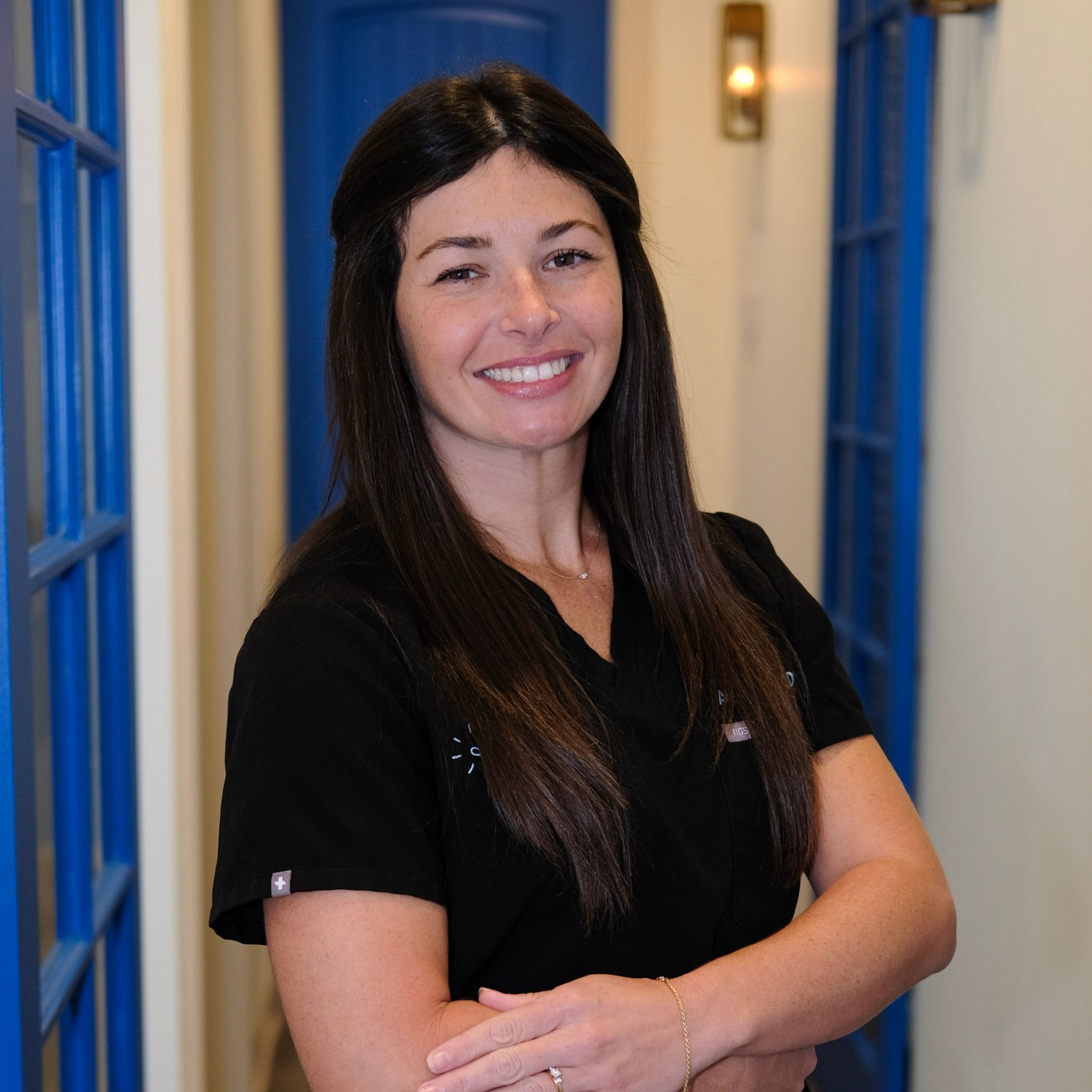 Smiling healthcare worker in black scrubs standing in a dental clinic