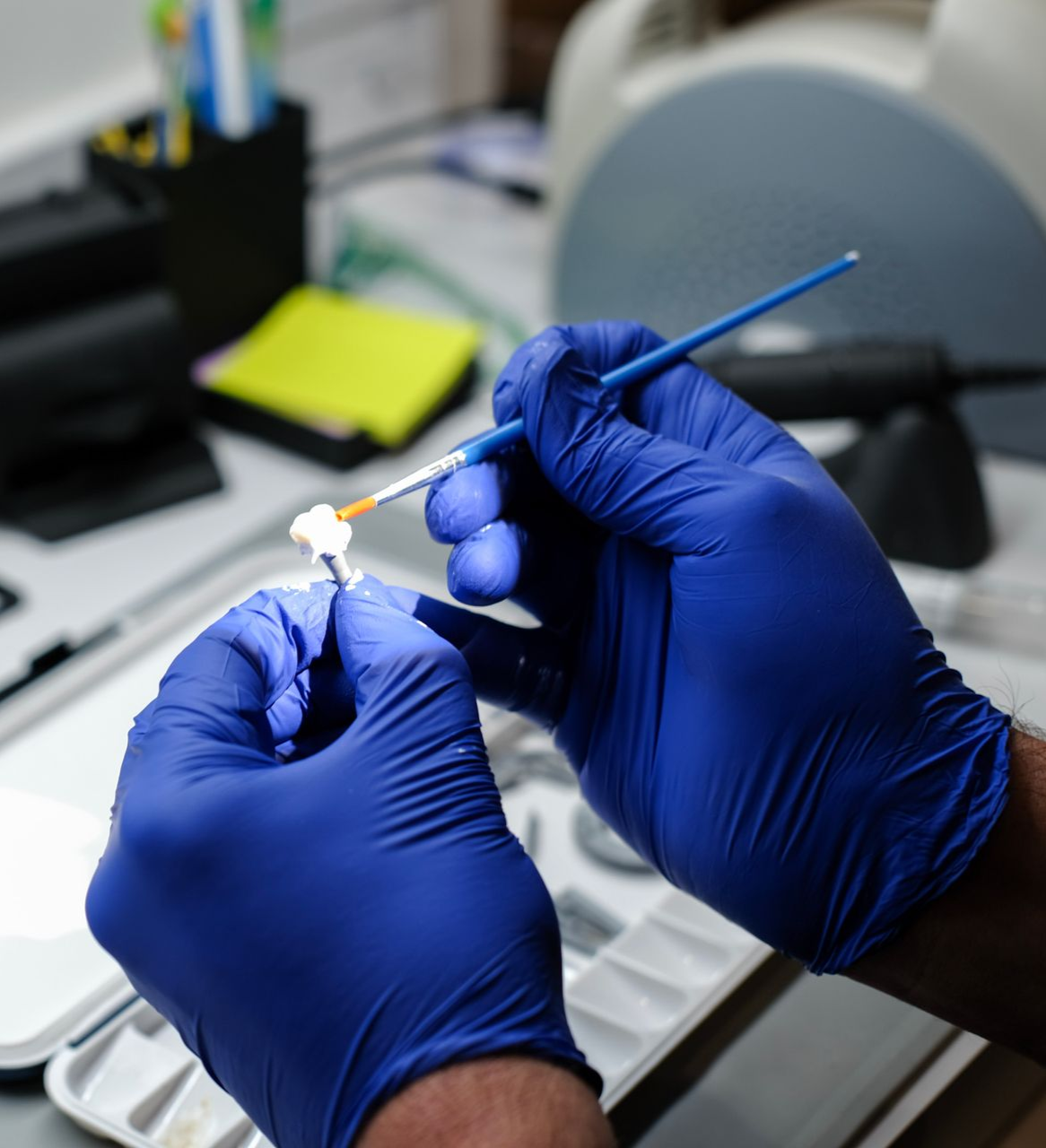 Gloved hands holding a dental tool with a purple polishing tip in a clinic setting