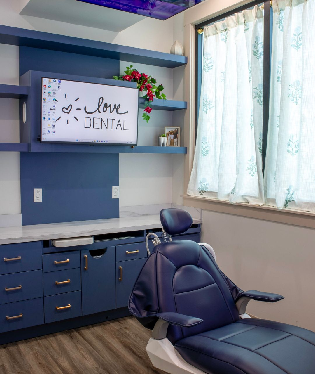Smiling patient reclining in a dental chair as a gloved clinician reaches toward them