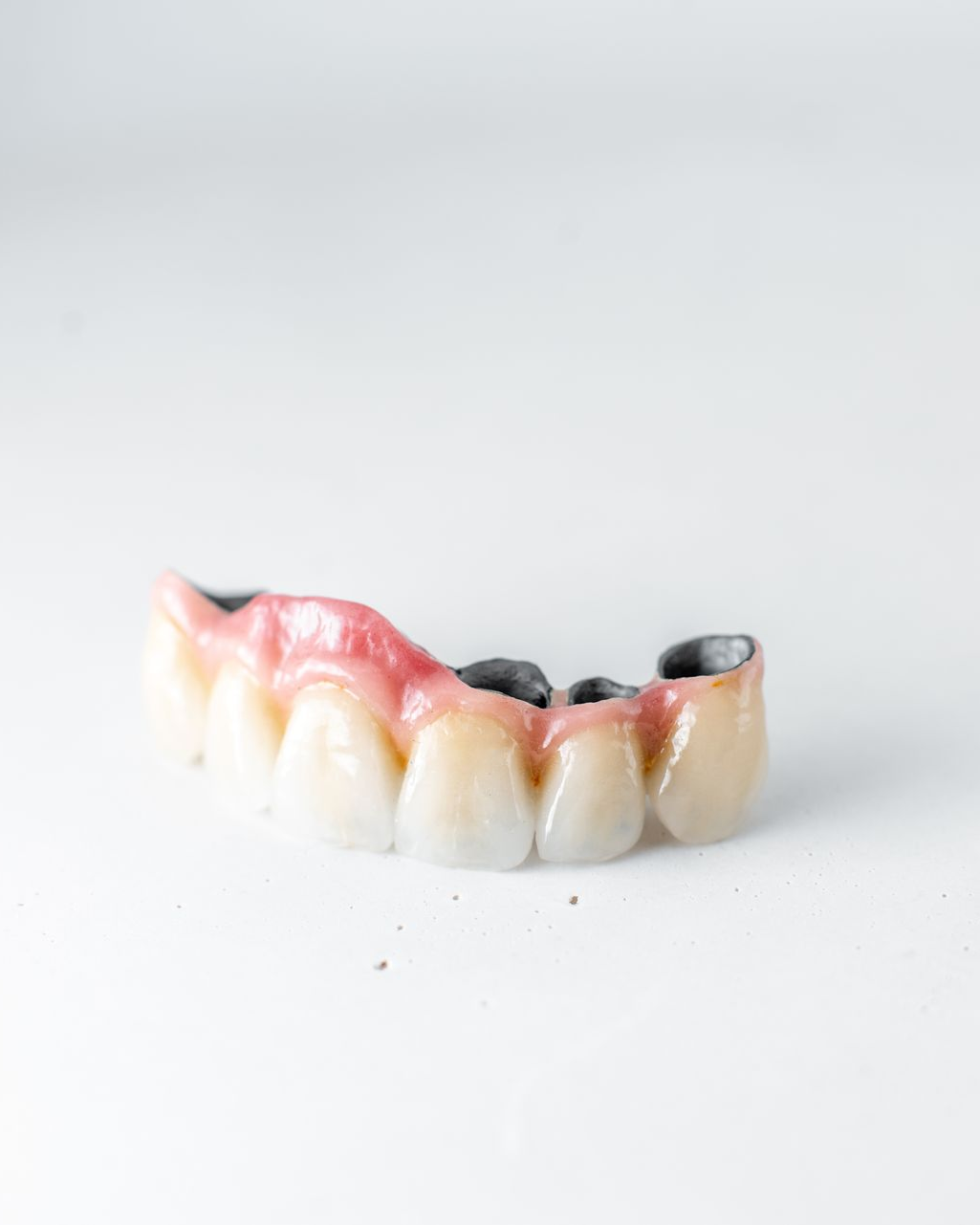 Small partial denture with pink gums and white teeth on a white background