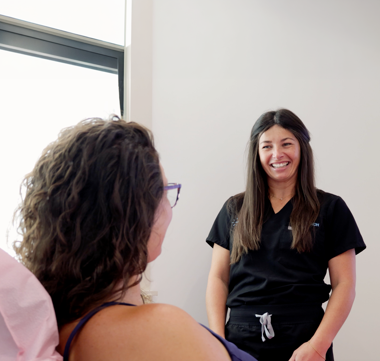 Woman smiling during dental treatment with a model jaw in a dentist's chair