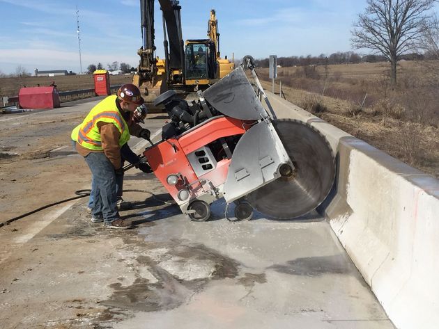 A man is using a circular saw to cut a piece of concrete