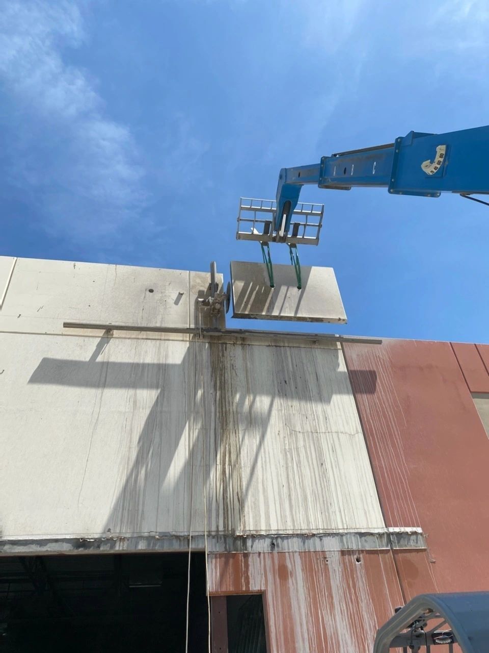 A crane is lifting a large piece of metal on top of a building