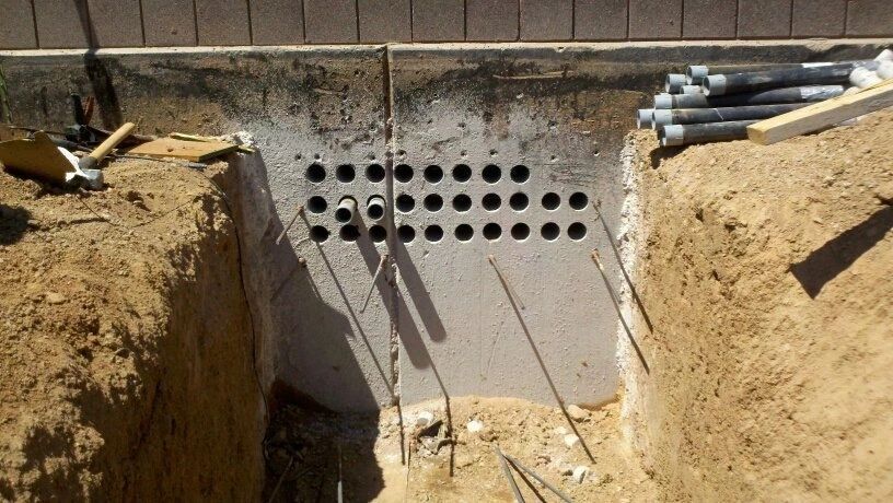 A concrete wall with holes in it is being built.