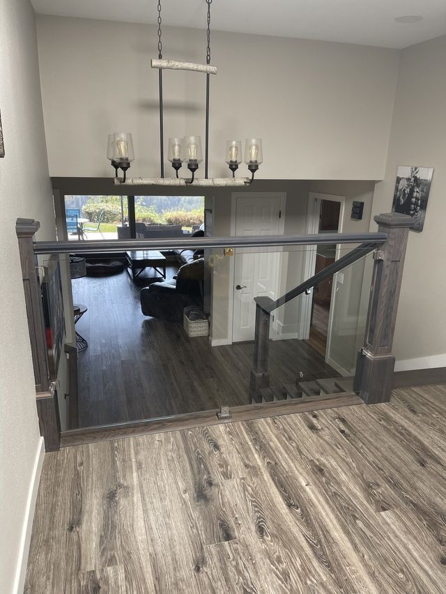 View from above of a staircase with glass railing, leading down to a living room.