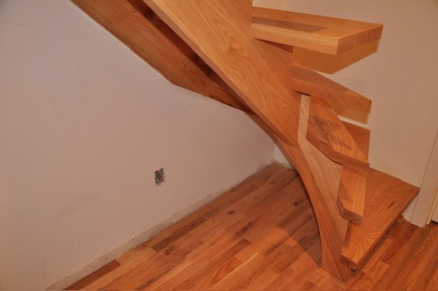 Wooden staircase with a floating design. Oak flooring. Beige walls.