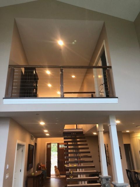Two-story interior with a balcony railing, staircase, and recessed lighting.
