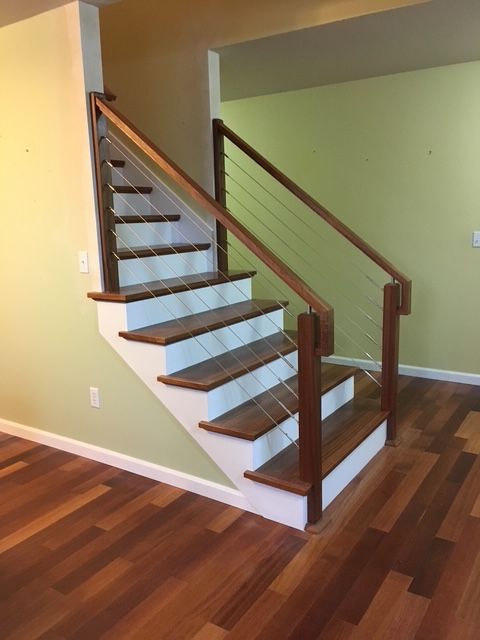 Wooden staircase with white risers, brown treads, and cable railings.