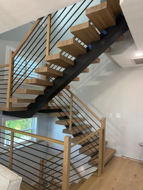 Modern wooden staircase with black metal railings and light-colored treads.