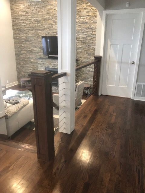 Interior view with dark hardwood floors, white pillars, stone wall, and a staircase.