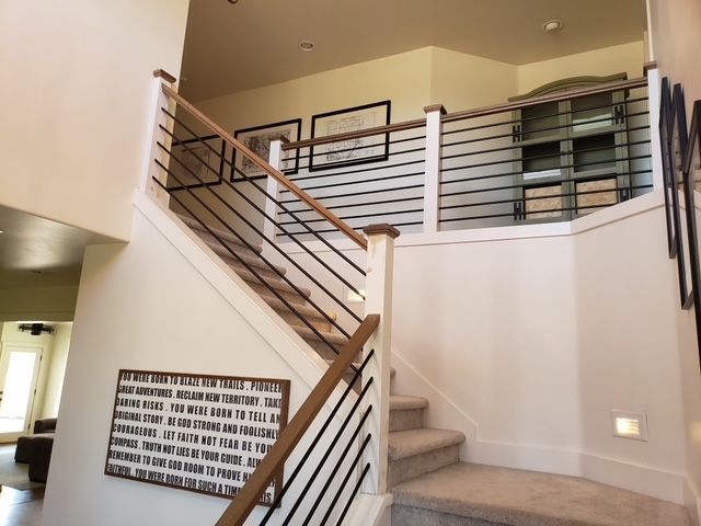 Staircase with wooden handrails, black metal balusters, and a quote sign on the wall.