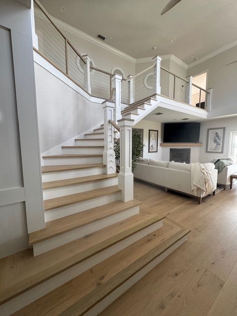 Wooden staircase in a bright, modern home with a view of a living room and fireplace.
