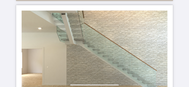 Modern staircase with glass railing against a textured wall.
