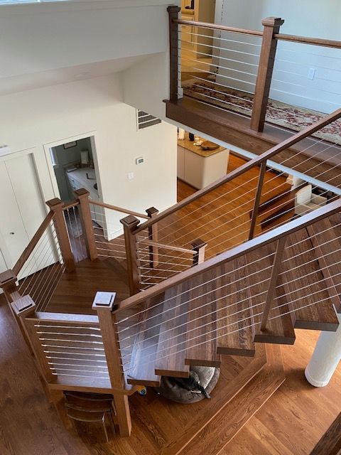 Wooden staircase with cable railings, leading to a second floor.