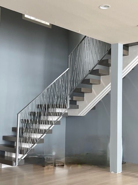 Gray floating staircase with intricate metal railing in a modern home.