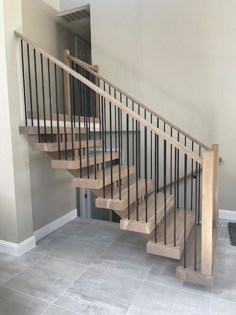 Wooden staircase with black metal railings, light-colored walls and tiled floor.