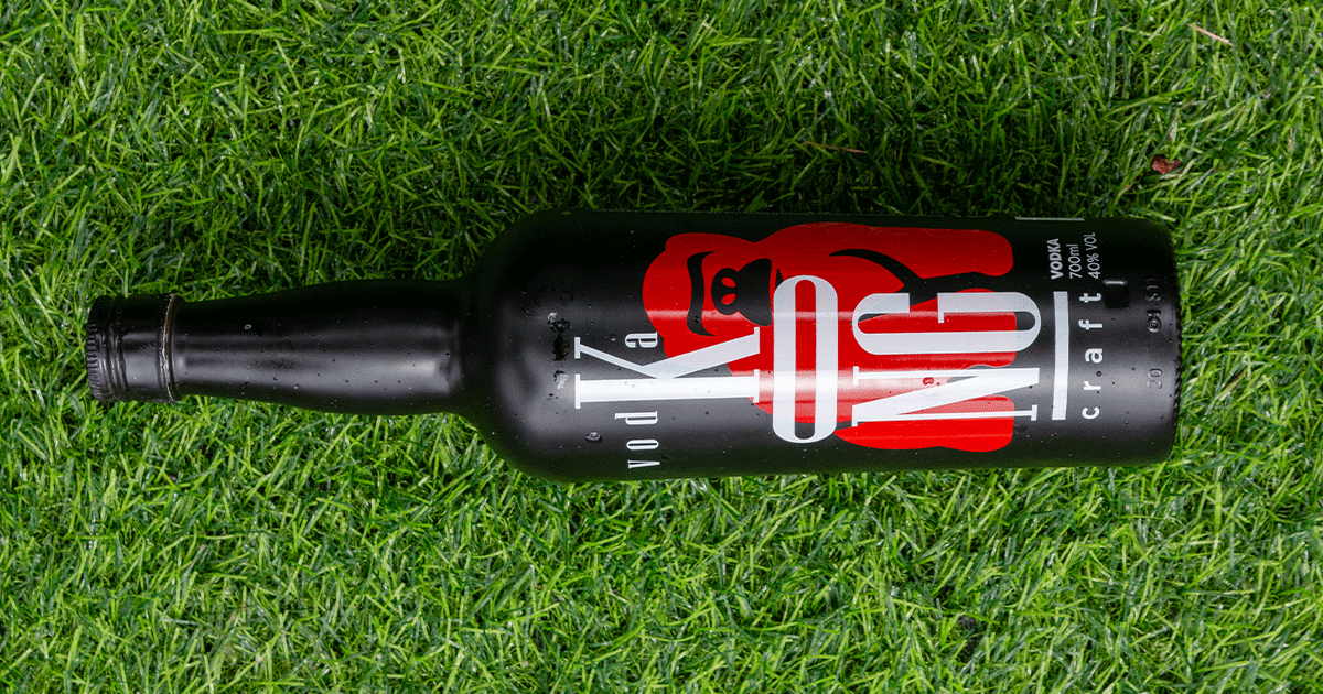 Uma garrafa de cerveja está no topo de um campo verdejante.