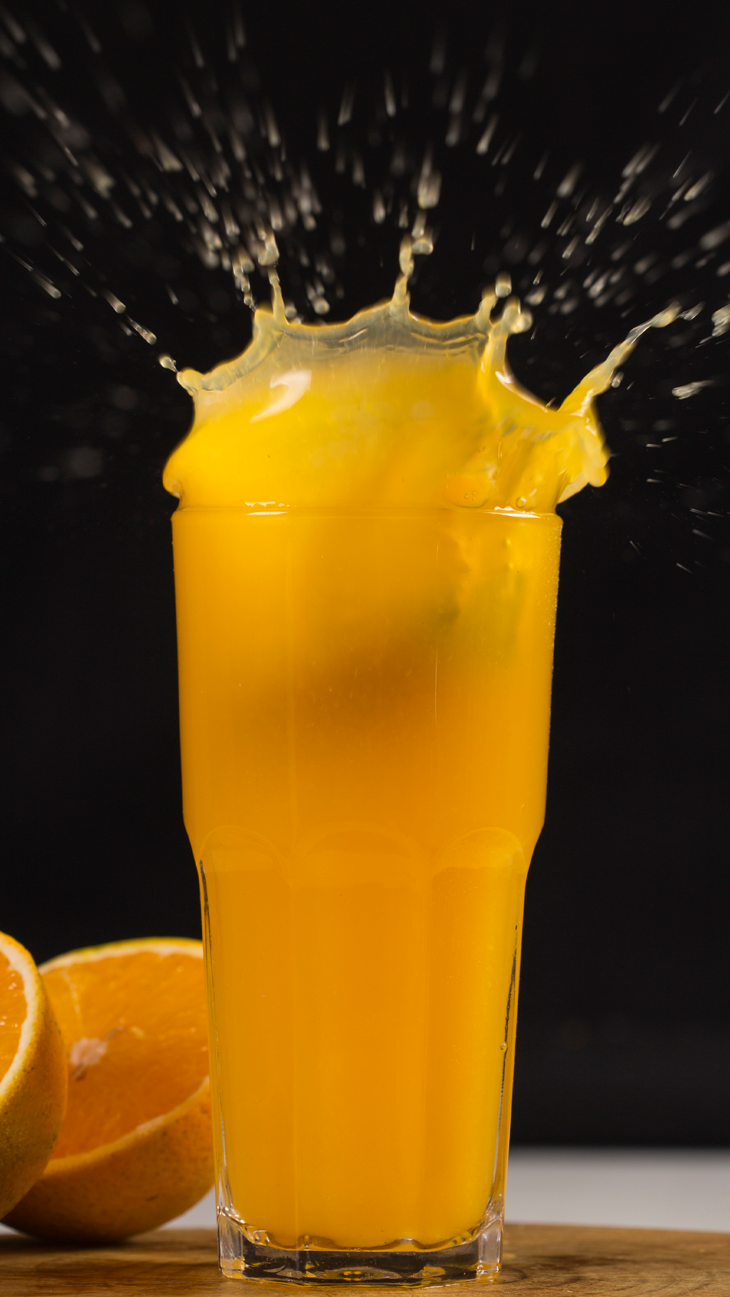 Um copo de suco de laranja com um respingo saindo dele.