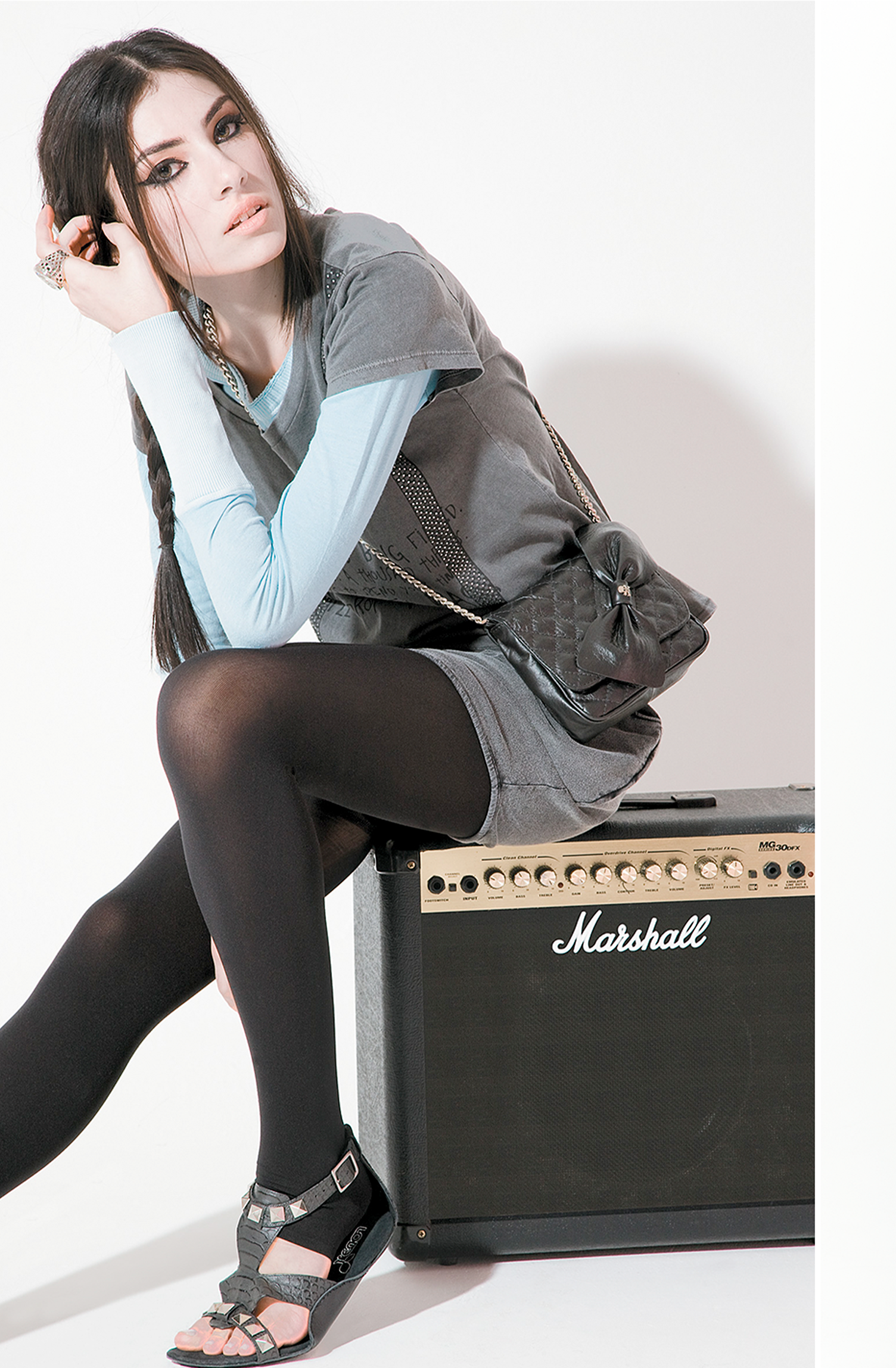 A woman is sitting on a marshall amplifier