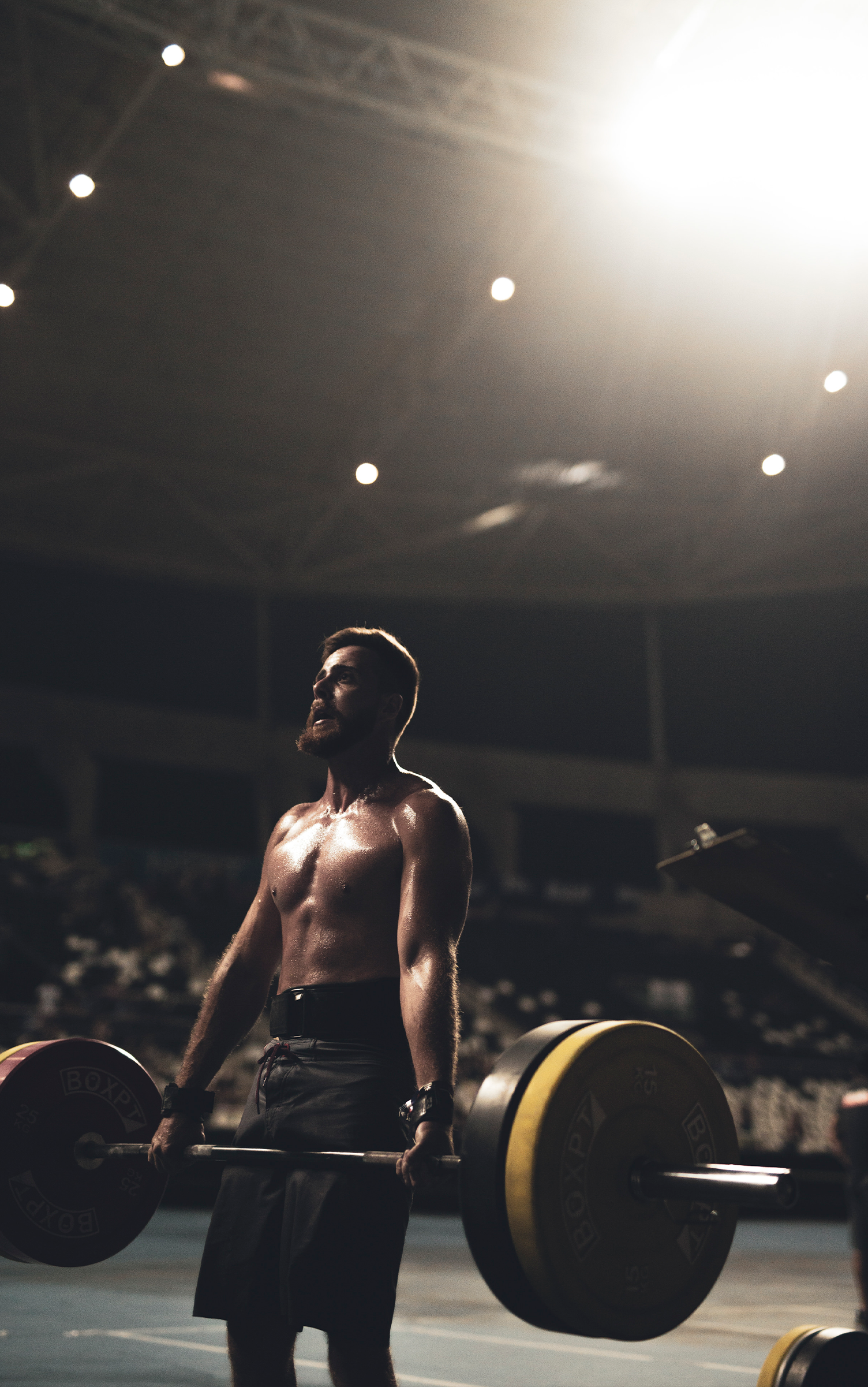 Um homem sem camisa está levantando uma barra em uma academia.