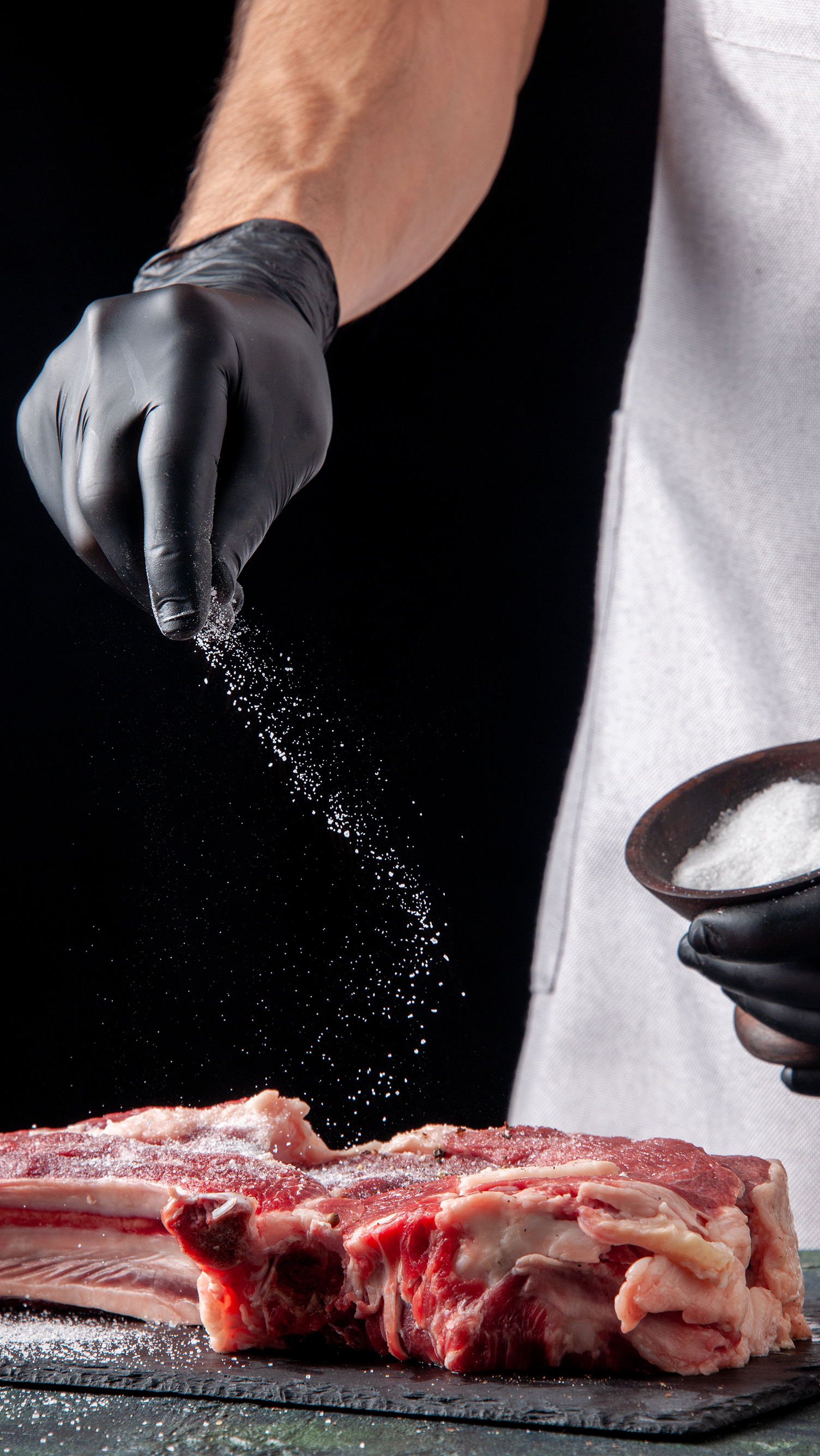 Turus Uma pessoa está espalhando sal em um pedaço de carne crua.