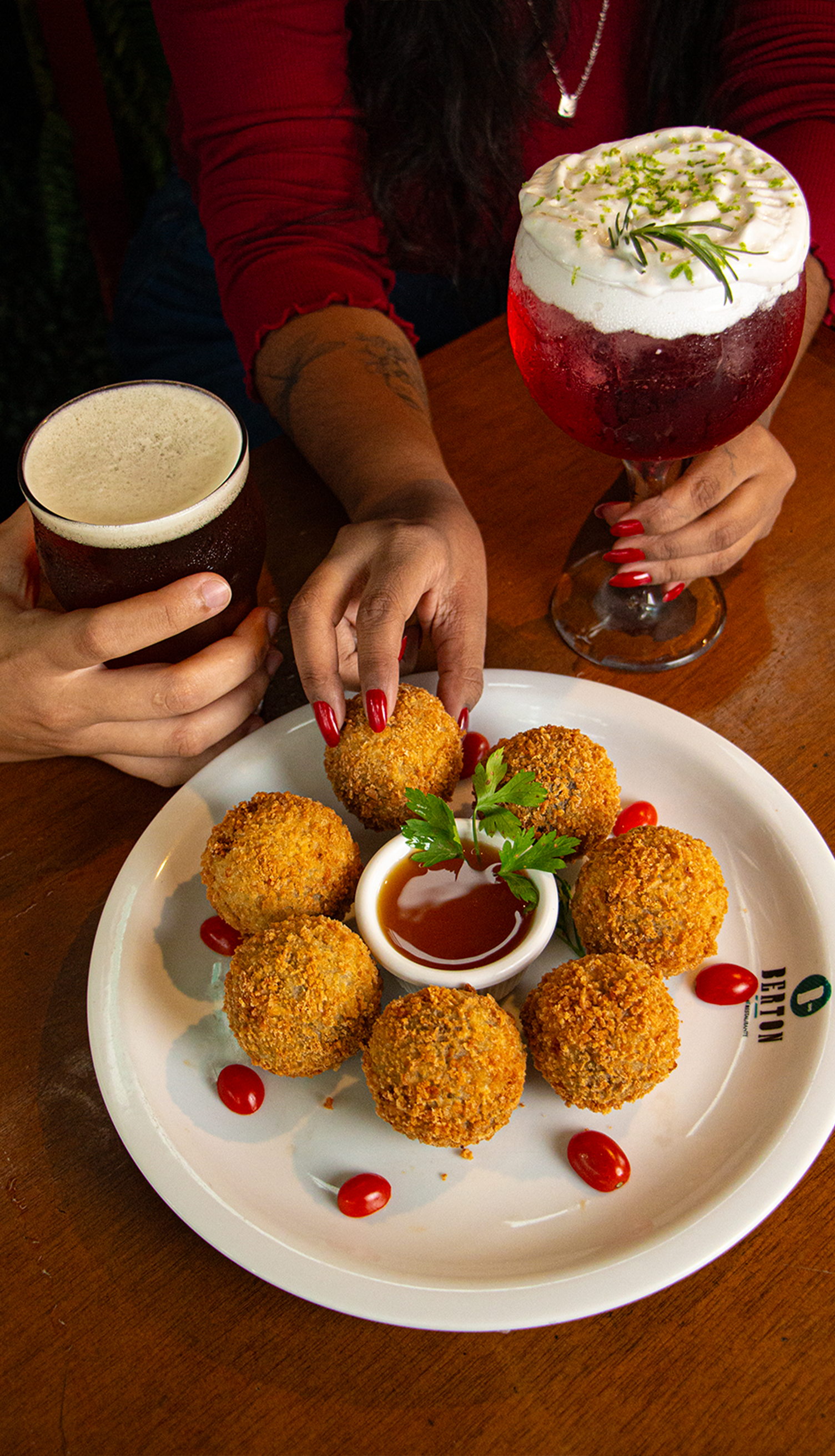 Duas pessoas estão sentadas à mesa comendo e bebendo cerveja.