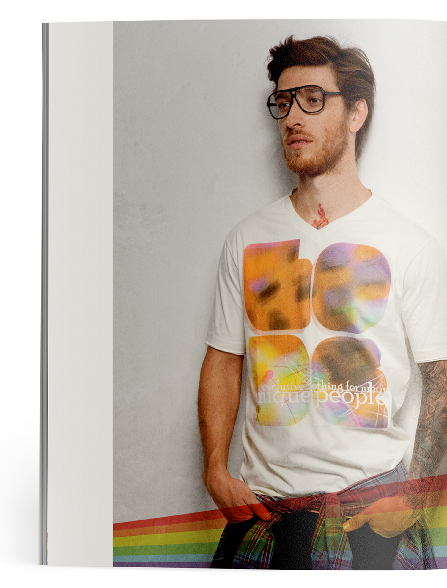 A man wearing glasses and a white t-shirt is standing in front of a rainbow wall.