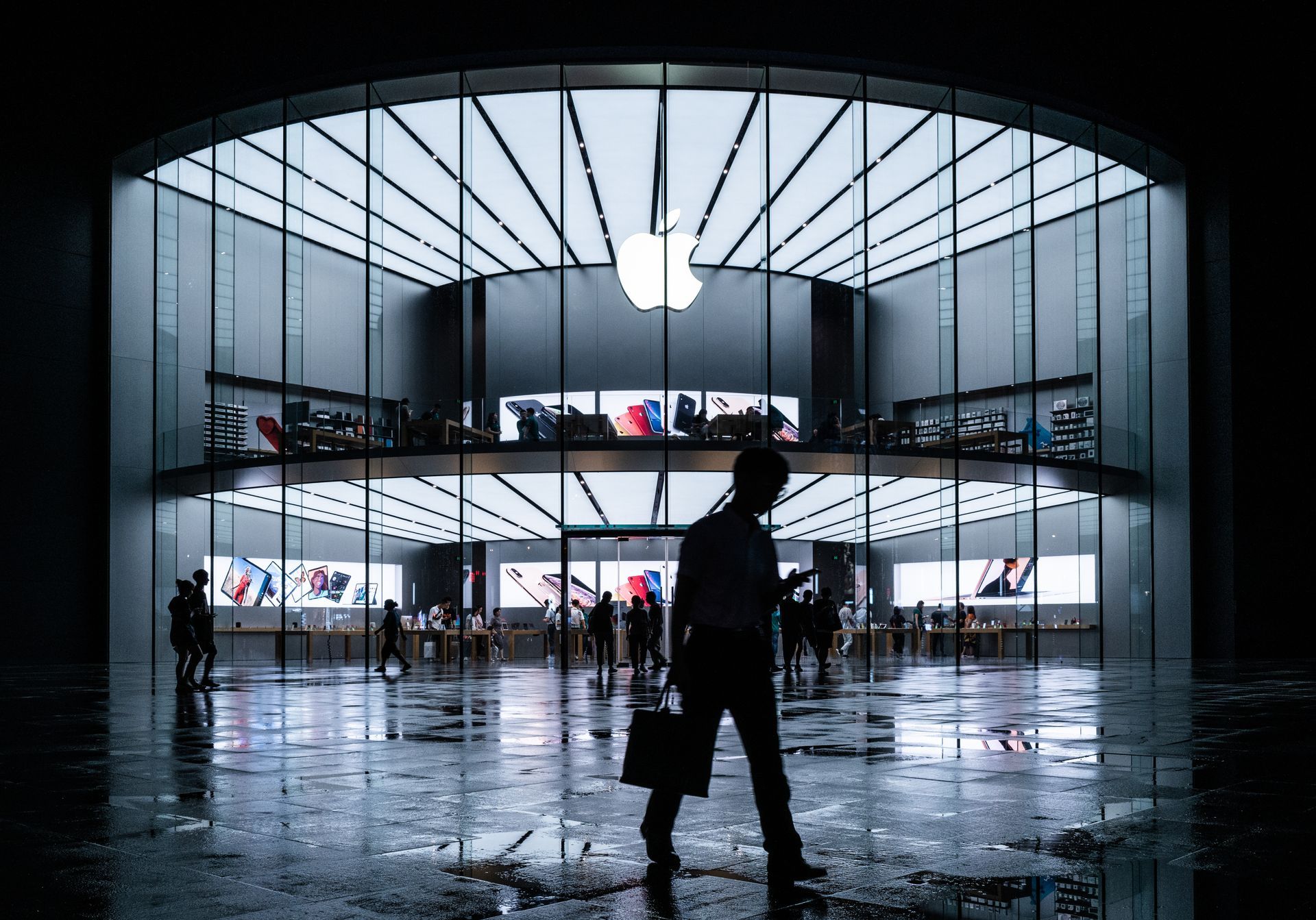 Um homem com uma pasta está caminhando em frente a uma loja da Apple.