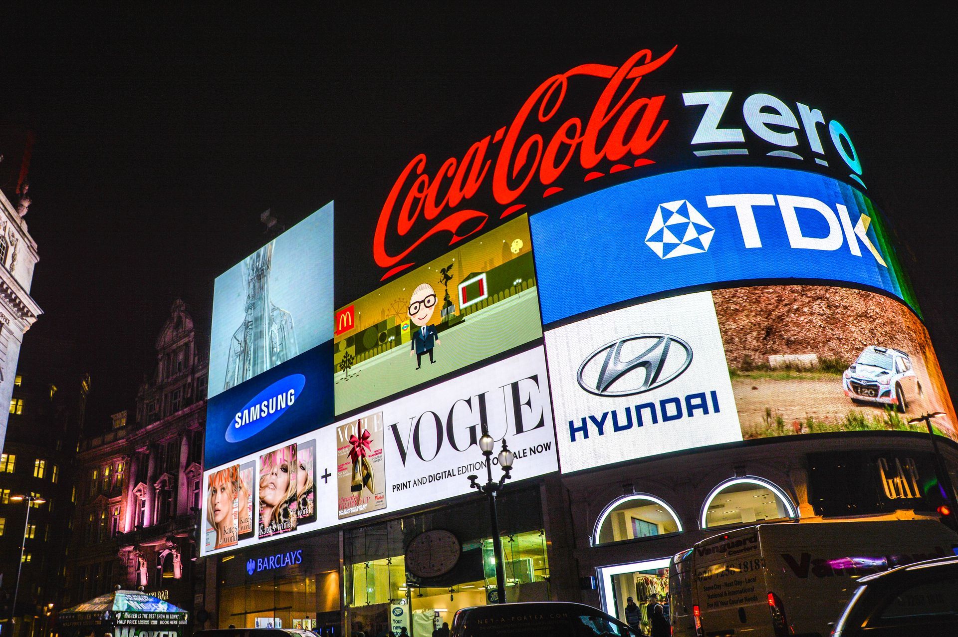 Um grande outdoor com coca cola, tdk, vogue e hyundai.