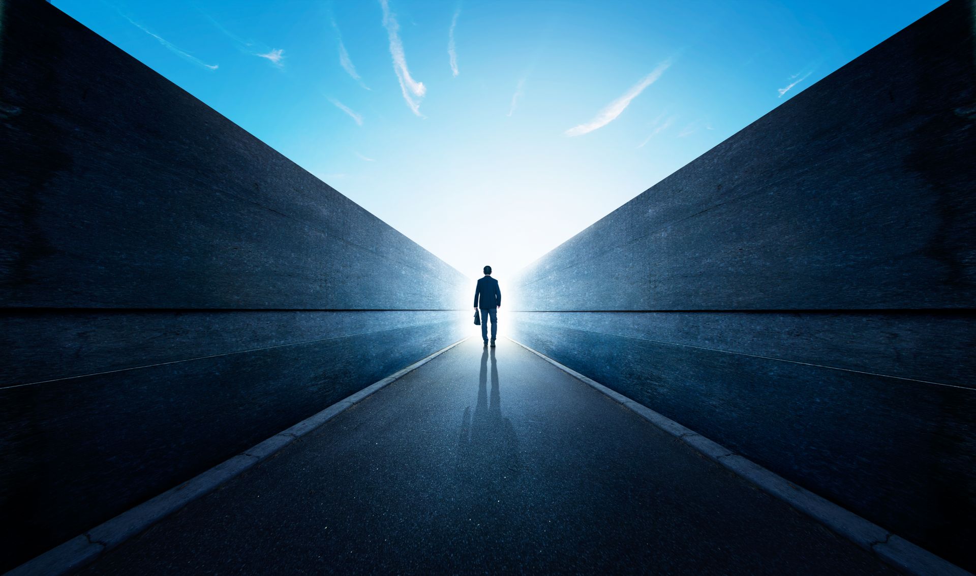 Um homem está caminhando por uma estrada com uma maleta na mão.