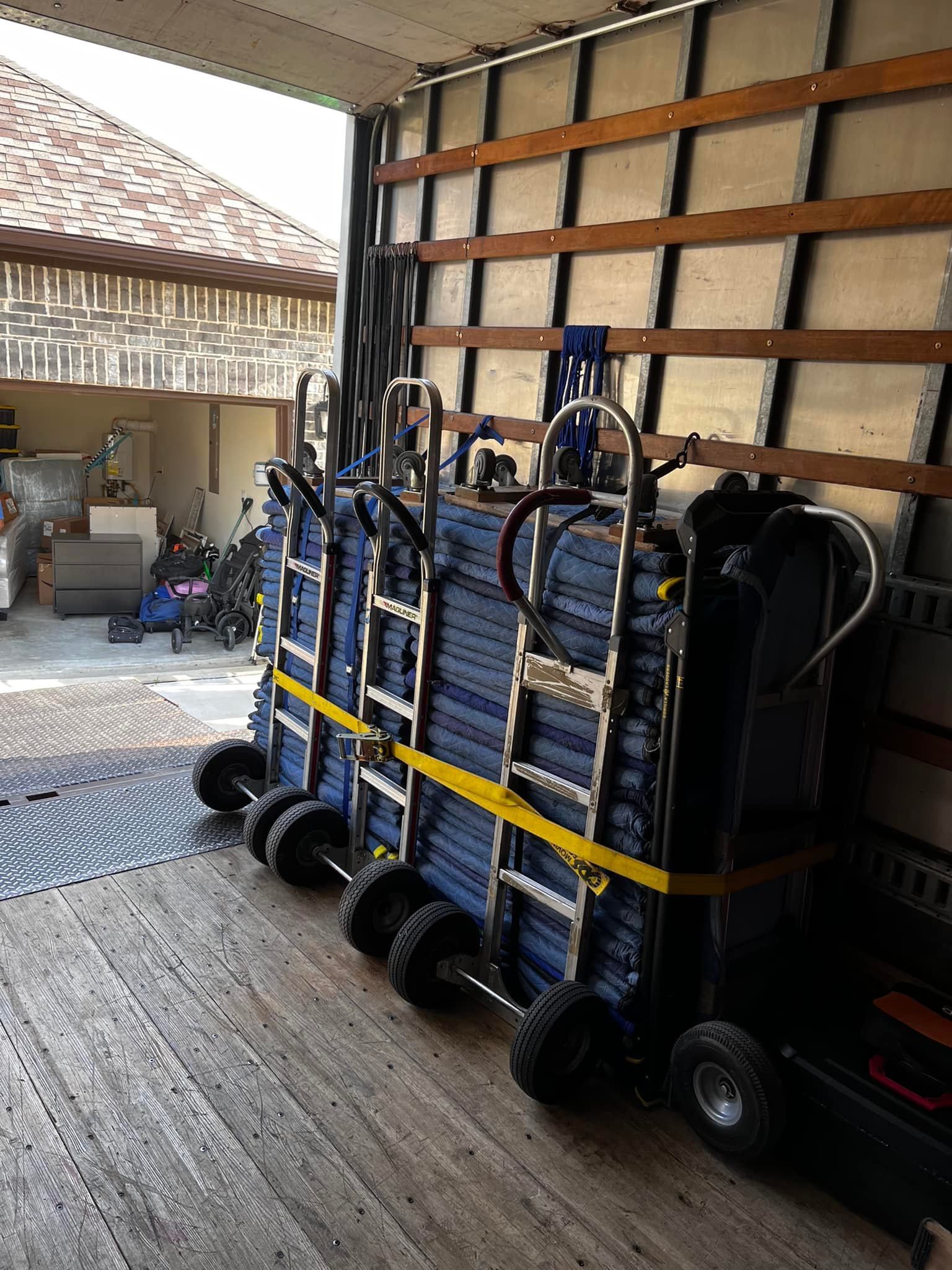 Dollies stacked with blue items secured inside a truck, ready for transport.