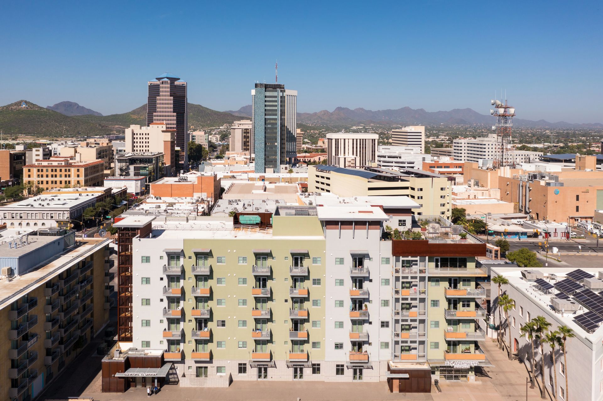 Aerial view of a city downtown with buildings of different heights and architectural styles under a clear blue sky.