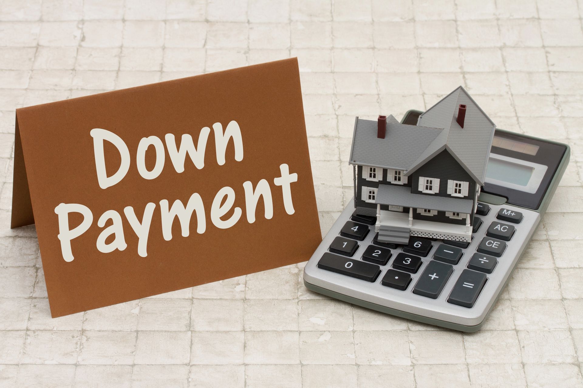Brown sign says Down Payment, with house model on calculator.
