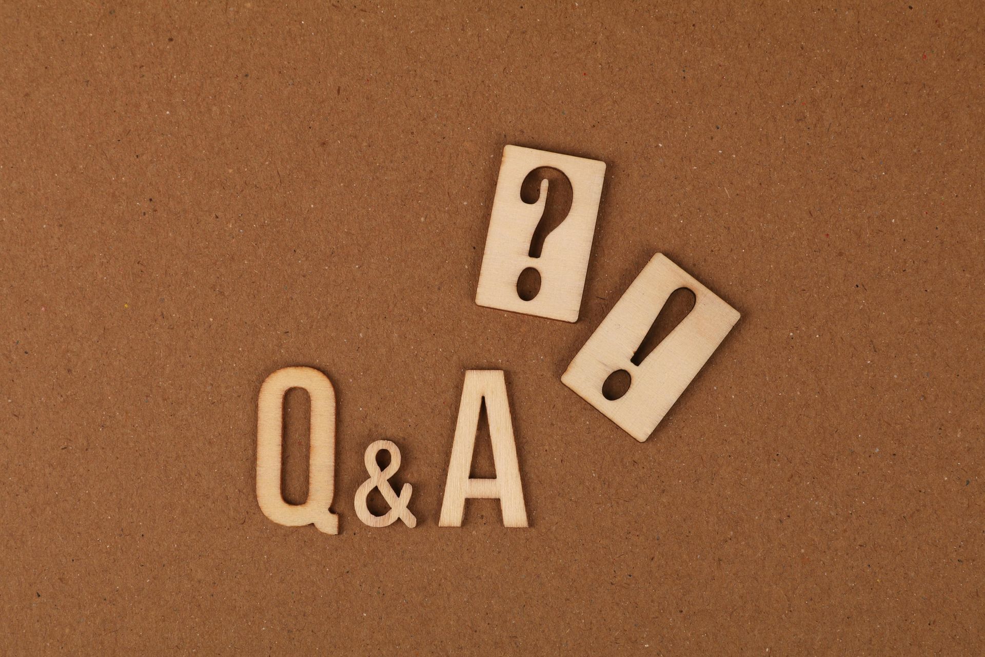 Q&A letters with a question mark and exclamation point on a brown surface.