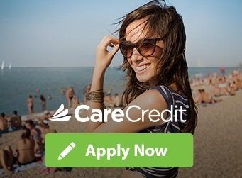 Woman on beach with sunglasses smiling, CareCredit logo and