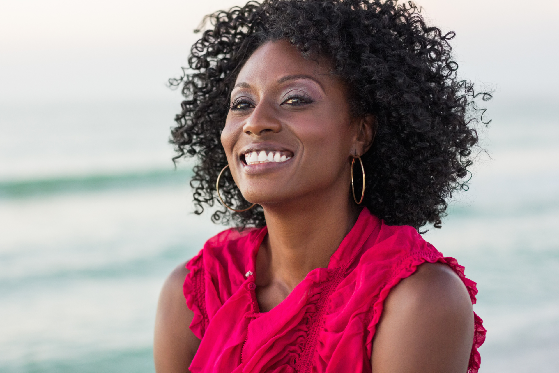 Smiling person in a bright pink top outdoors near the beach