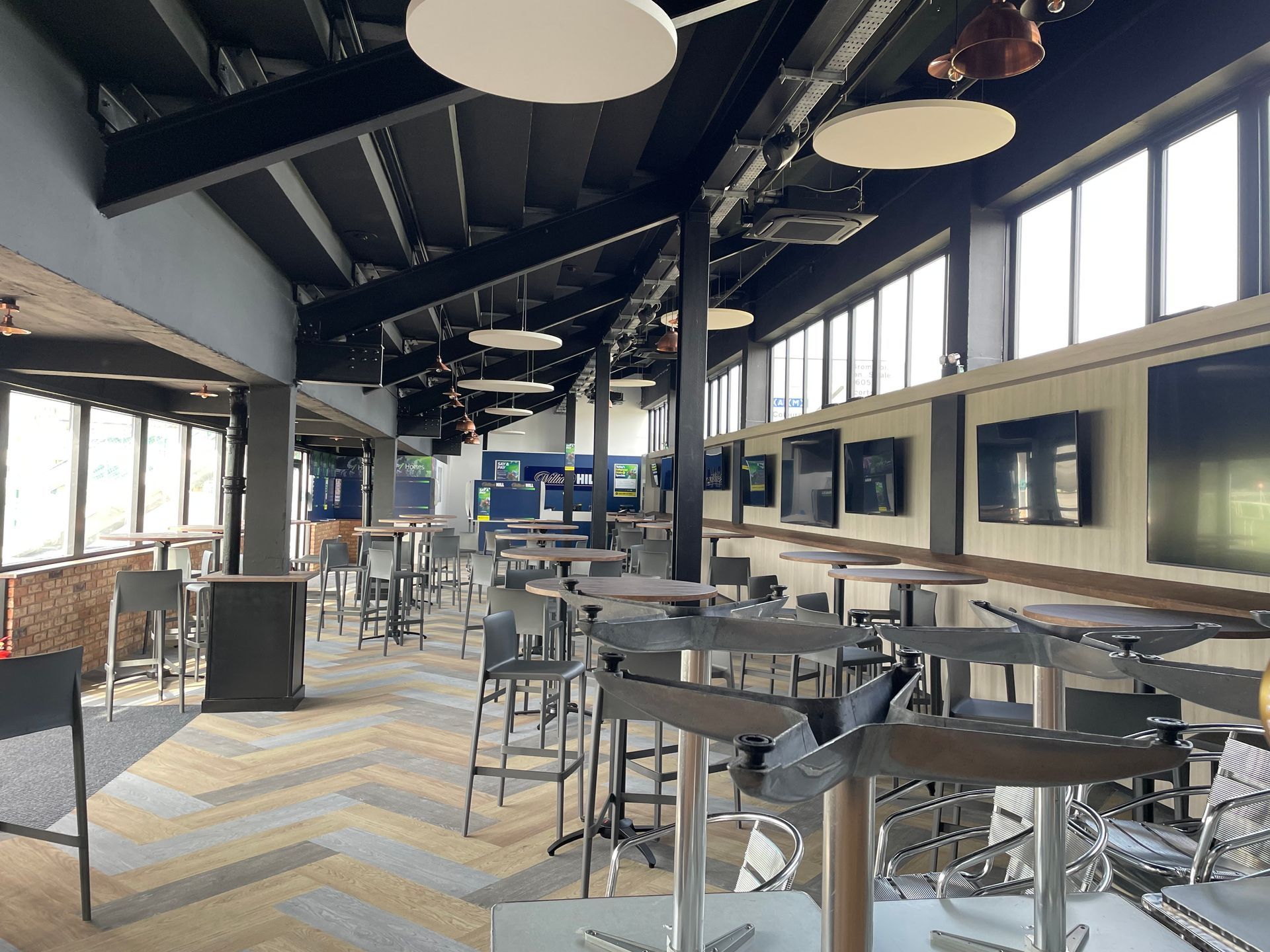 A large room with tables and chairs and a lot of windows.