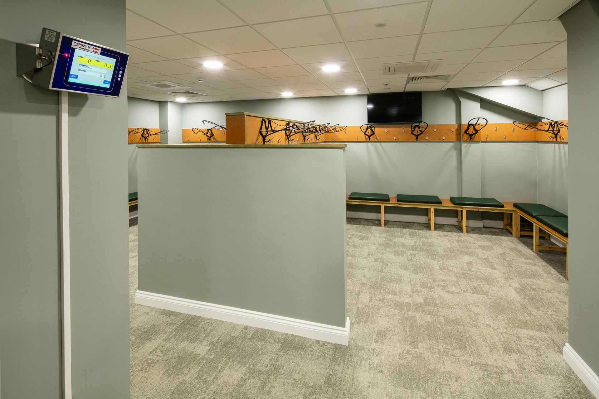 A locker room with benches and a tv on the wall.