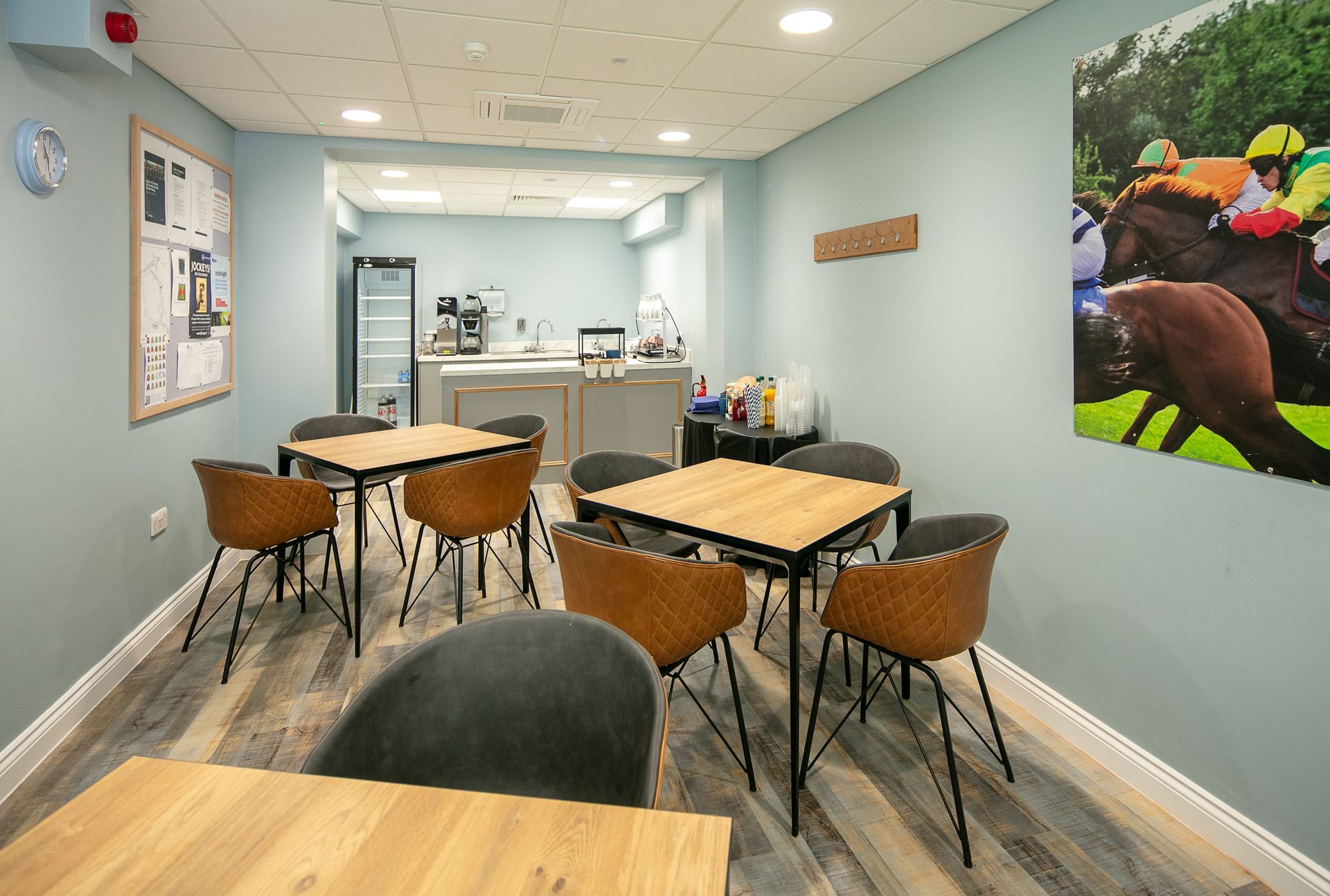 A room with tables and chairs and a picture of horses on the wall.