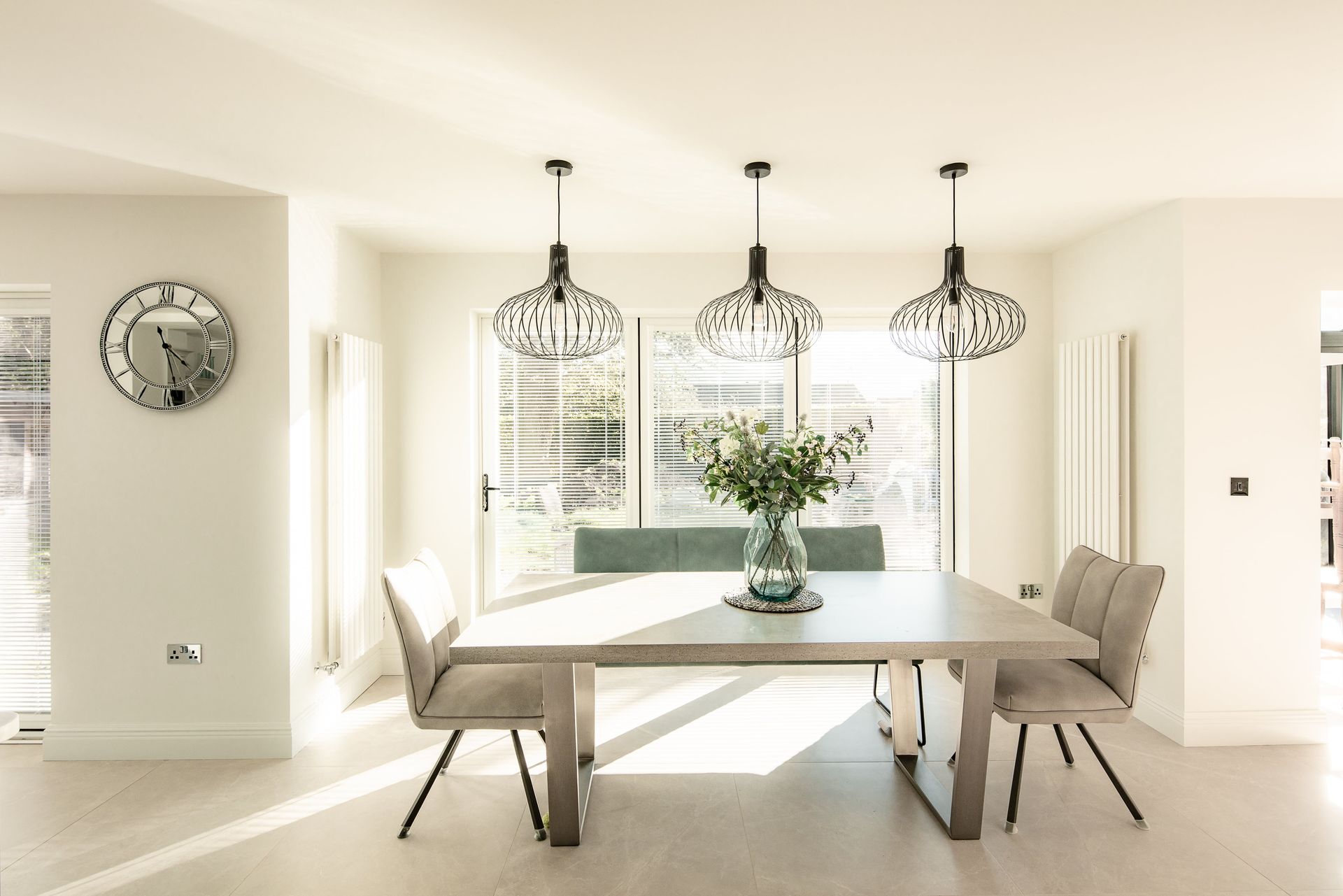 A dining room with a table and chairs and a vase of flowers on it.