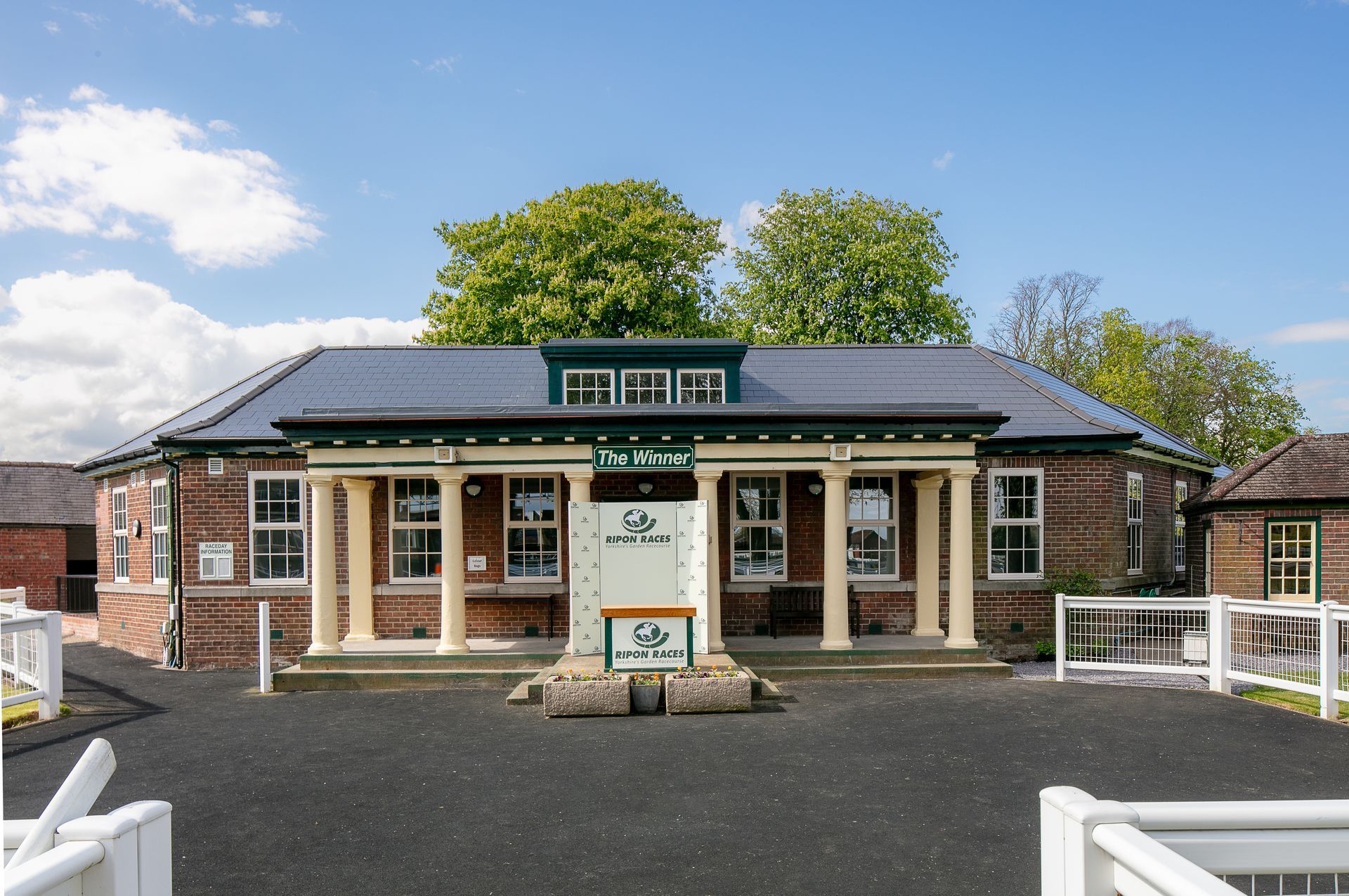 A brick building with a green roof and a sign that says tea shop
