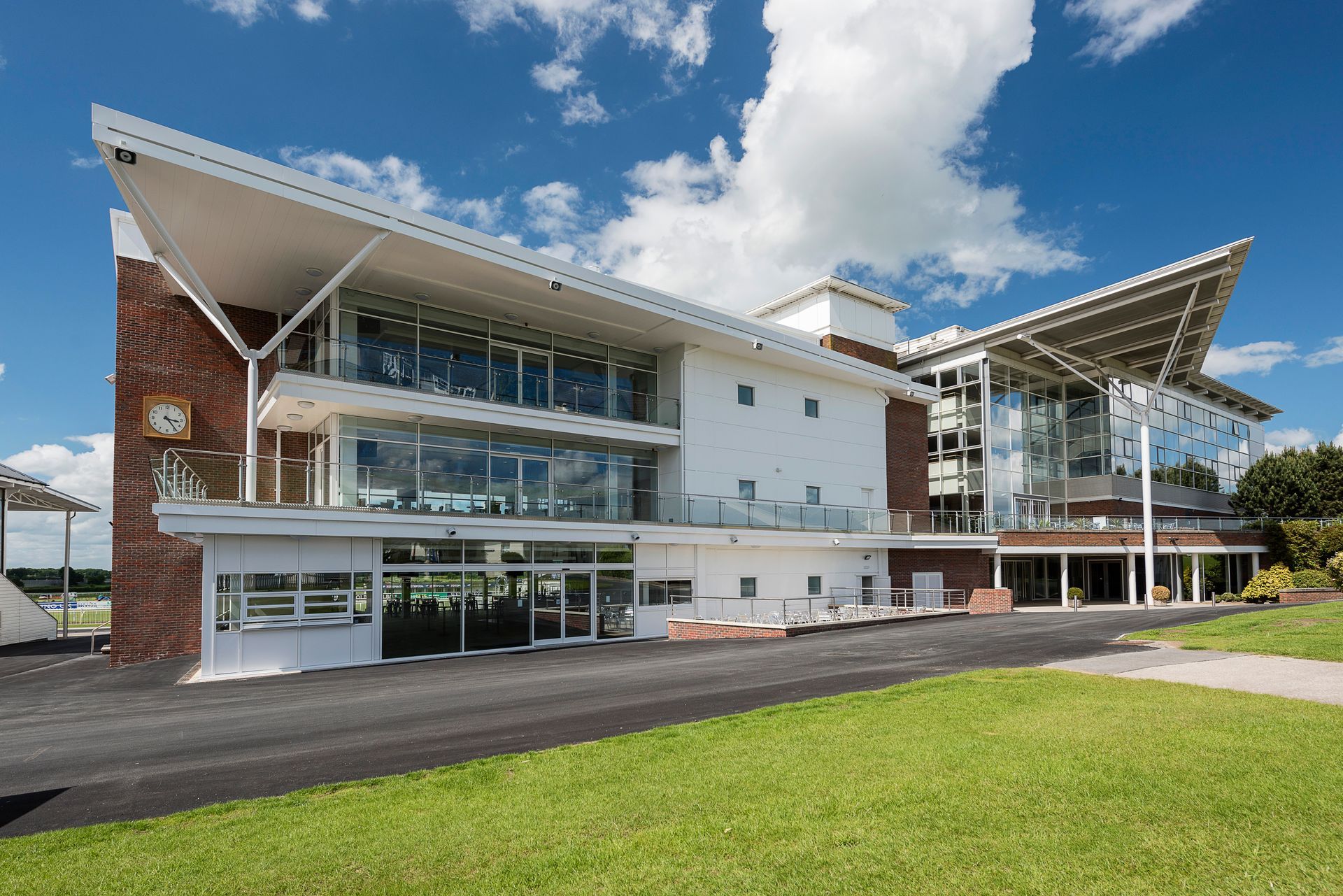 A large white building with a lot of windows is sitting on top of a lush green field.