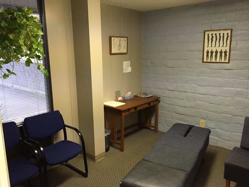 A waiting room with a table and chairs and a picture on the wall.
