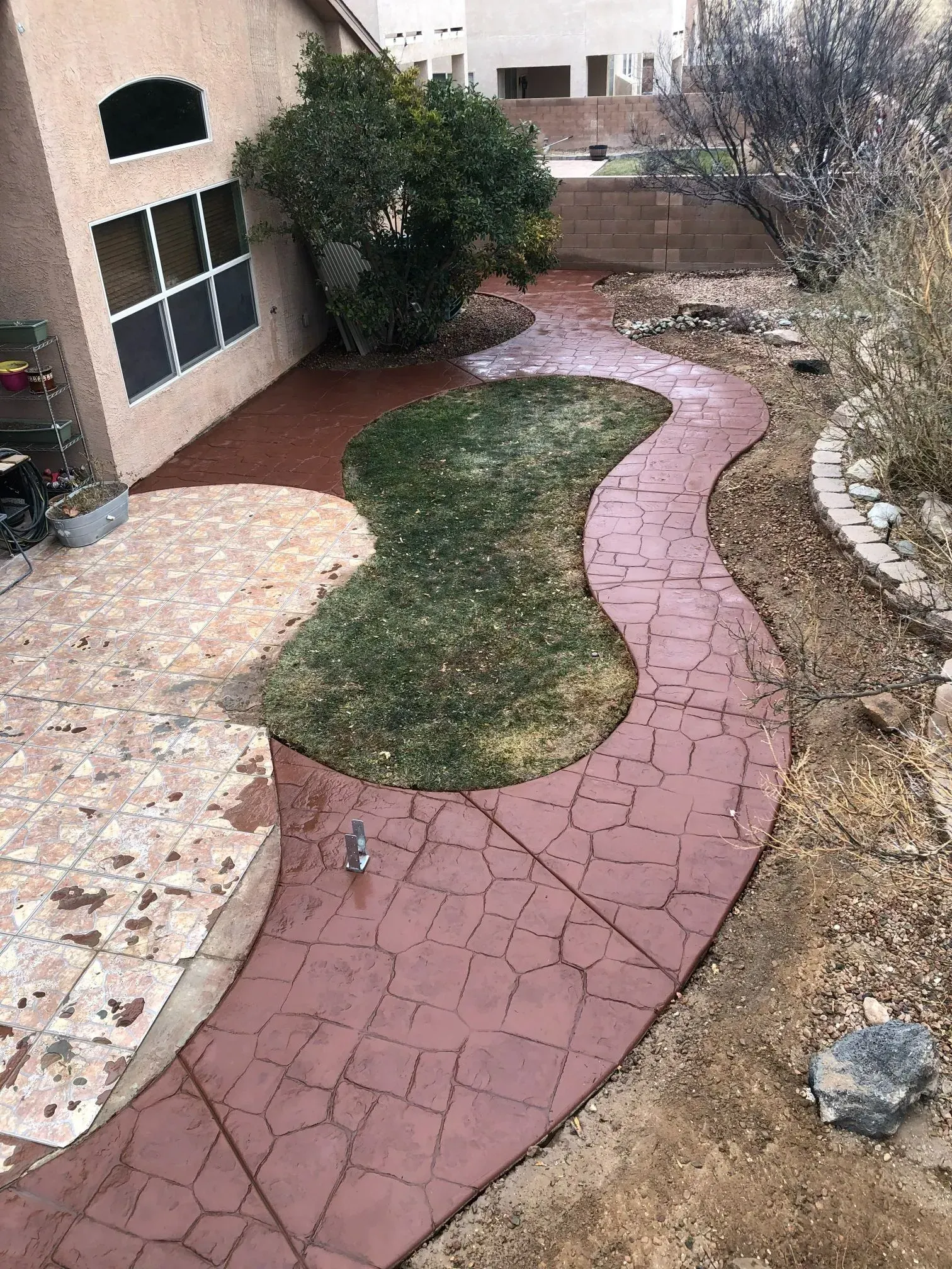 A brick walkway leading to a house in a backyard.