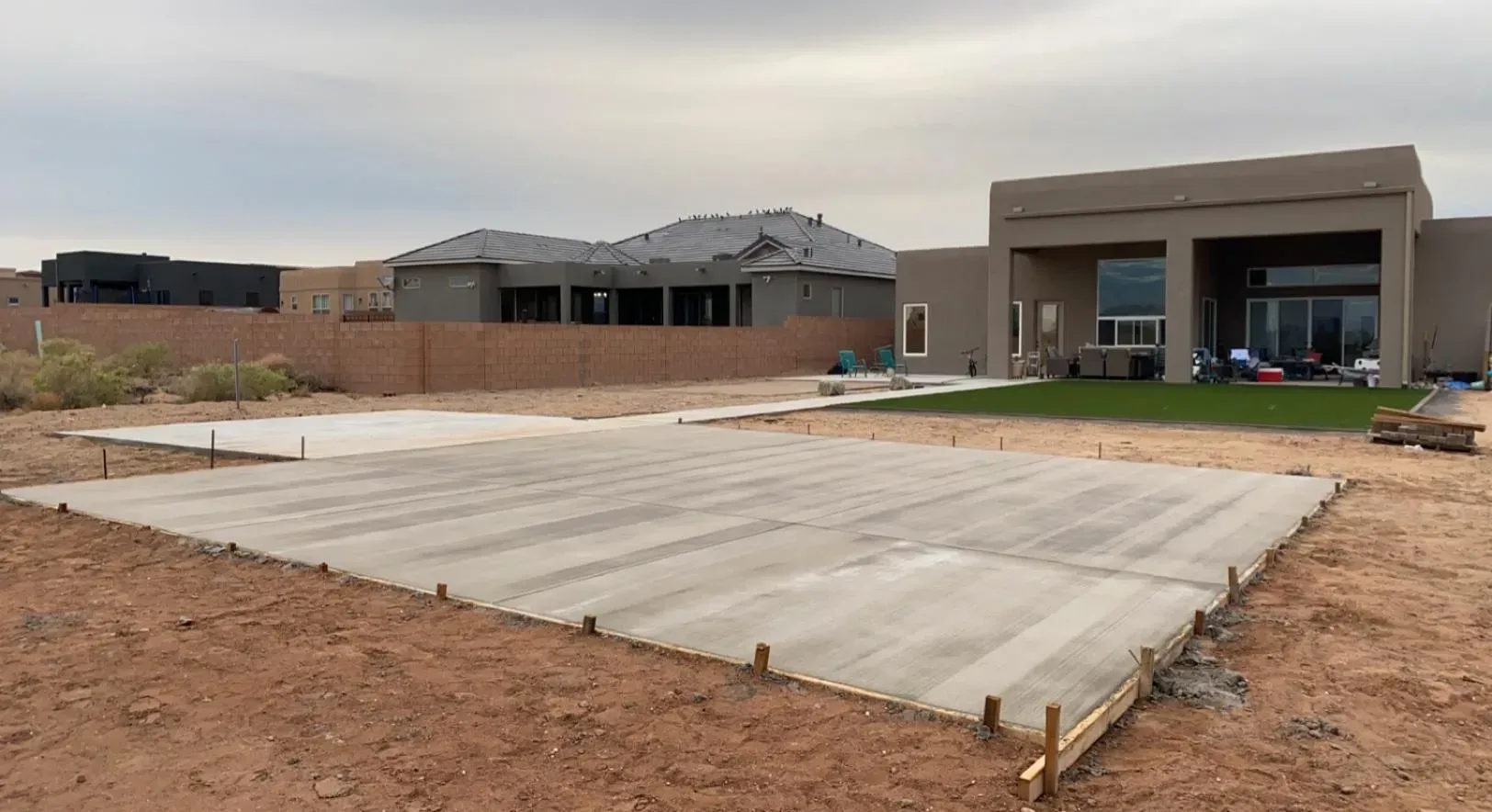 A large house is being built in the desert with a large concrete slab in the foreground.