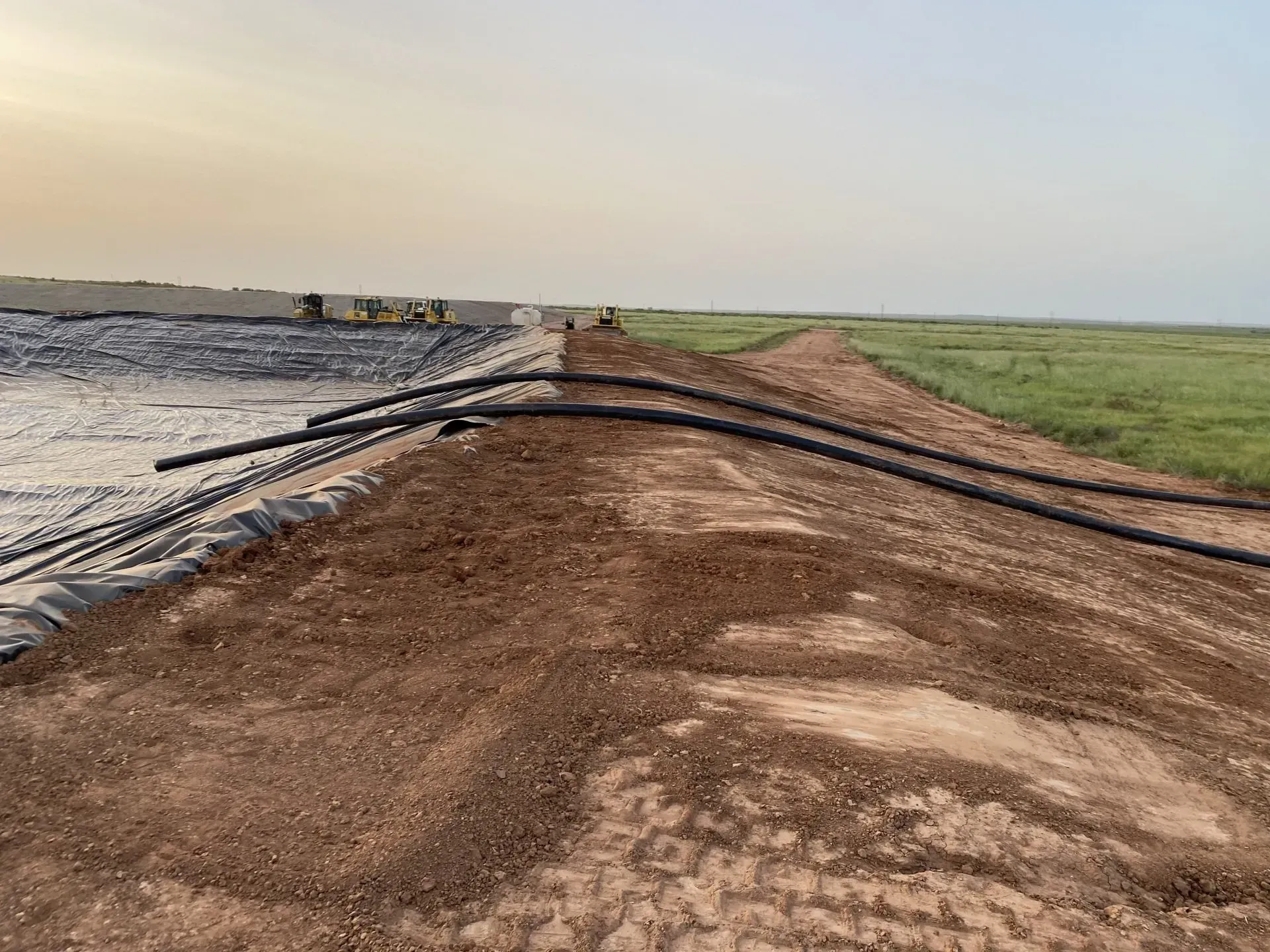 A dirt road leading to a large body of water.