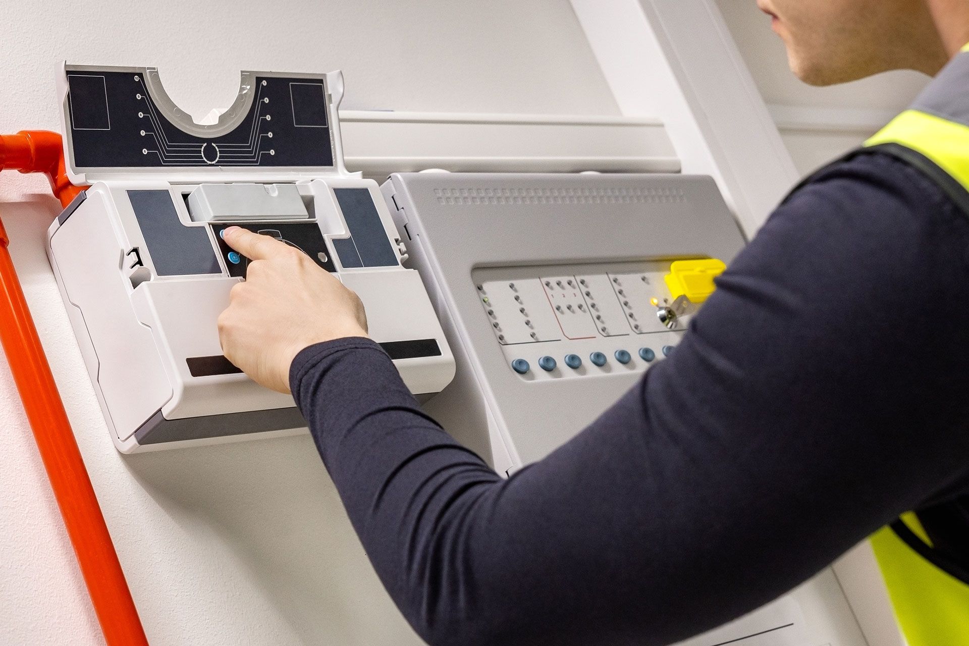 Technician operating an electrical control panel with an open cover and lit buttons
