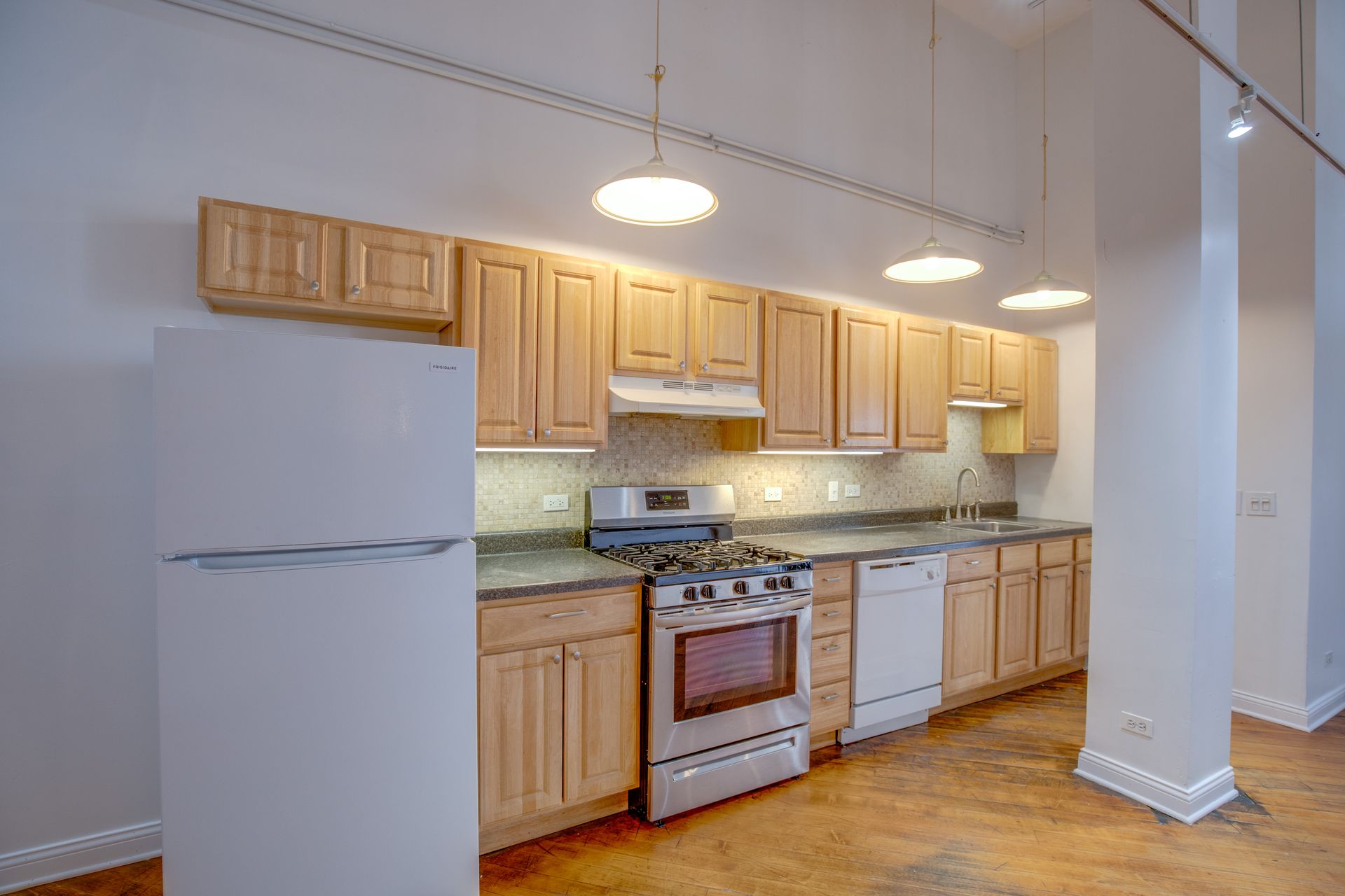A kitchen with wooden cabinets , stainless steel appliances , a refrigerator and a stove.